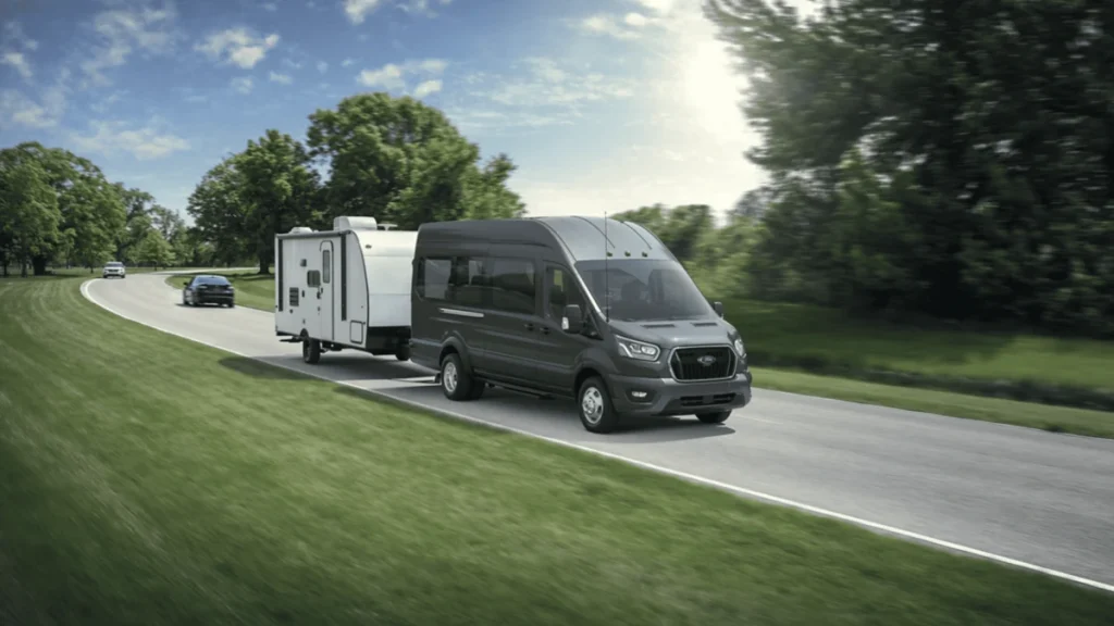 The 2025 Ford Transit® Van, equipped for towing, is seen with a trailer in Cleveland, OH, highlighting its practical design.