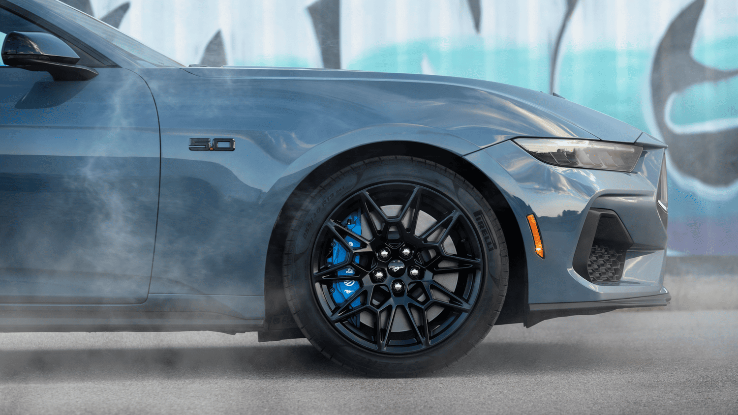 2025 Ford Mustang® GT wheel and side badge in Euclid, OH, with sporty Pirelli tires and blue brake calipers.