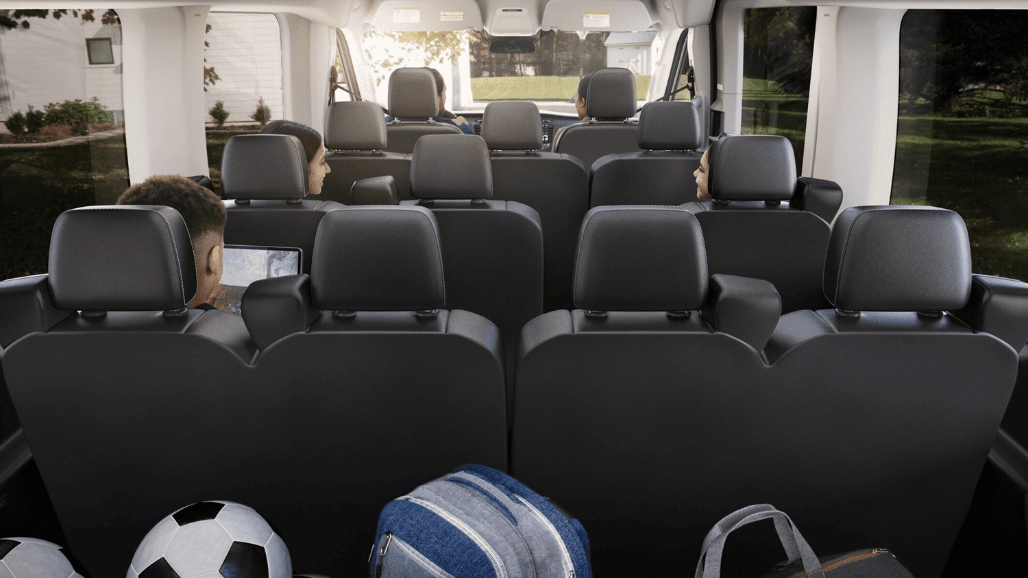 Rear cabin view of the 2025 Ford Transit® in Euclid, OH with passengers seated and backpacks visible, ideal for group travel.