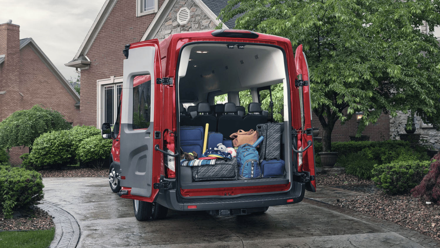 Open rear doors of the 2025 Ford Transit® in Euclid, OH filled with luggage and sports gear, highlighting its spacious cargo capacity.